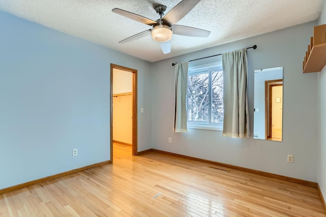 empty room with ceiling fan, a textured ceiling, and light hardwood / wood-style flooring