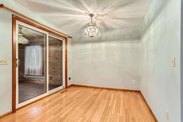 spare room with wood-type flooring, a chandelier, and a textured ceiling