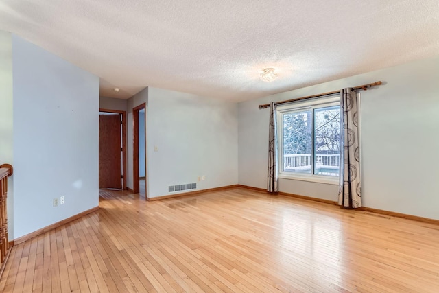 unfurnished room featuring a textured ceiling and light wood-type flooring