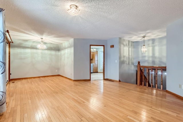 spare room featuring a chandelier, hardwood / wood-style floors, and a textured ceiling