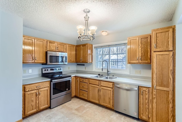 kitchen featuring sink, an inviting chandelier, stainless steel appliances, a textured ceiling, and decorative light fixtures