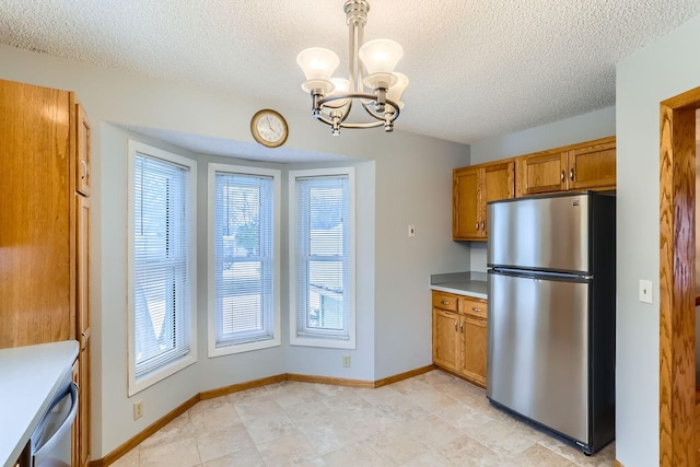 kitchen with a textured ceiling, a notable chandelier, stainless steel refrigerator, and decorative light fixtures