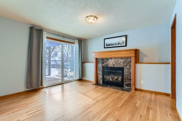 unfurnished living room featuring a premium fireplace, a textured ceiling, and light hardwood / wood-style floors