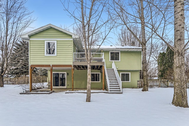 snow covered rear of property with a wooden deck