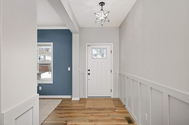 foyer entrance featuring an inviting chandelier, crown molding, and light hardwood / wood-style floors