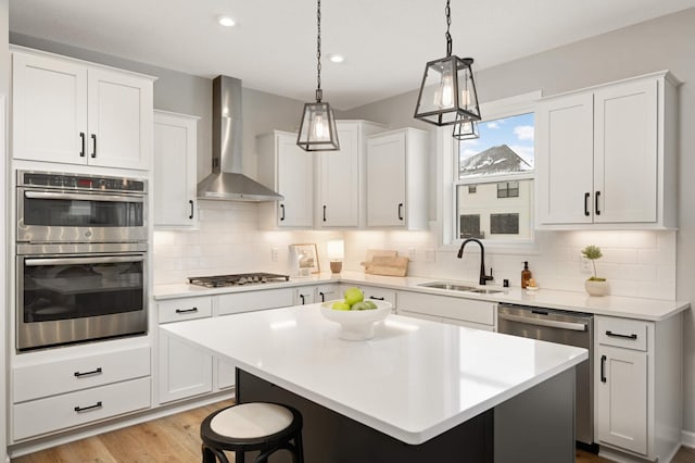 kitchen with a center island, appliances with stainless steel finishes, sink, and wall chimney range hood