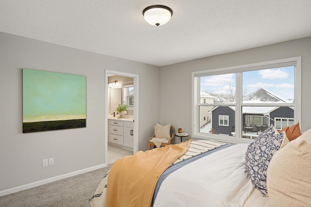 bedroom with connected bathroom, light colored carpet, and a textured ceiling