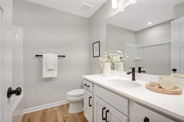 bathroom with hardwood / wood-style flooring, vanity, toilet, and walk in shower