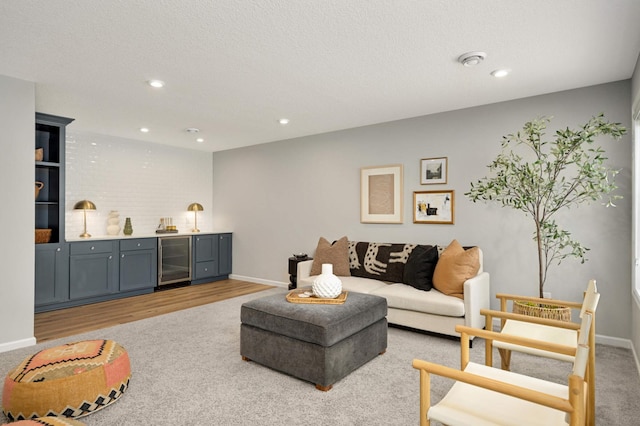 living room with bar, light hardwood / wood-style flooring, beverage cooler, and a textured ceiling