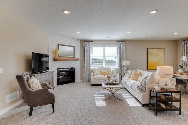 living room with light carpet, a large fireplace, and a textured ceiling