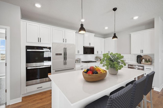 1683 Oak Creek Ct, Chaska, MN 55318 - kitchen with stainless steel appliances, wood finished floors, decorative backsplash, recessed lighting, and a textured ceiling