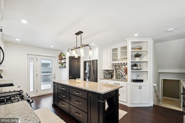 kitchen featuring white cabinetry, a kitchen island, stainless steel refrigerator with ice dispenser, and decorative light fixtures