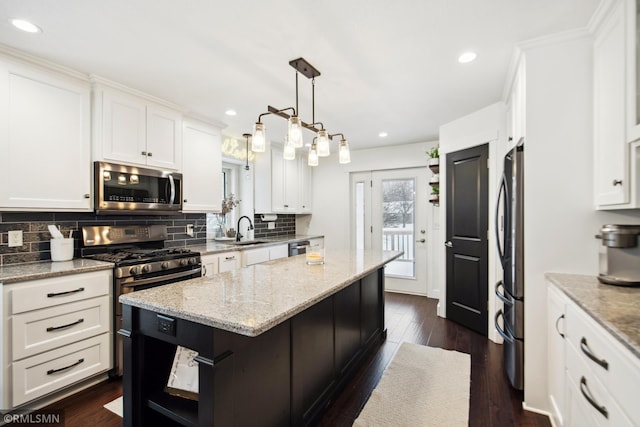 kitchen featuring white cabinets, a center island, appliances with stainless steel finishes, and hanging light fixtures