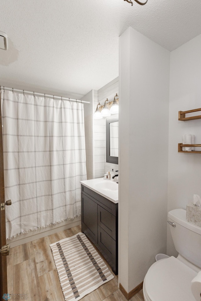 full bathroom with hardwood / wood-style flooring, toilet, a textured ceiling, shower / bath combo, and vanity