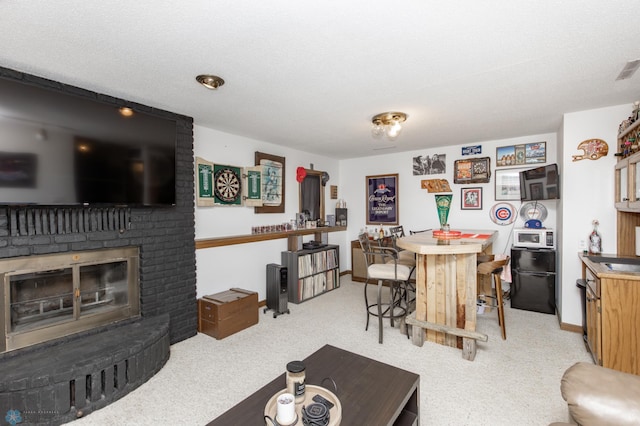 dining area with a brick fireplace, a textured ceiling, and light colored carpet