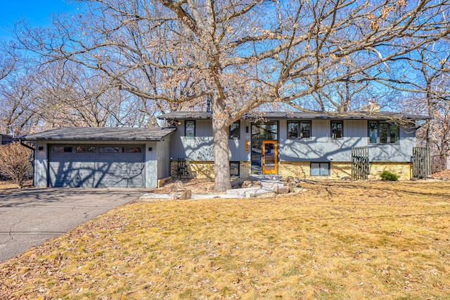 view of front of property featuring aphalt driveway, a front yard, a garage, brick siding, and a chimney