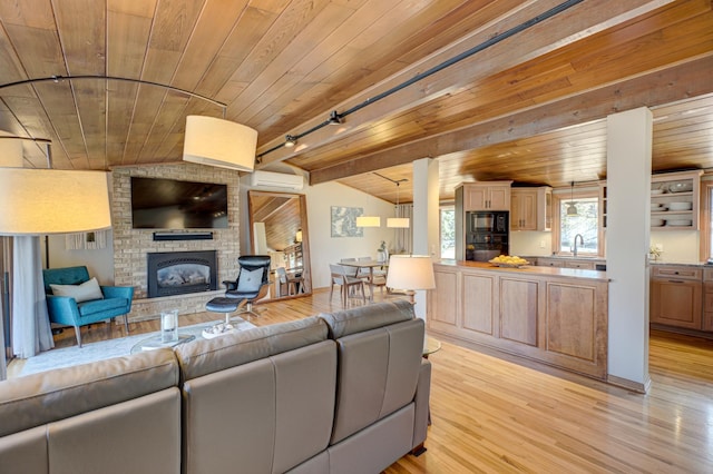 living room with a brick fireplace, an AC wall unit, lofted ceiling with beams, light wood-style flooring, and wooden ceiling