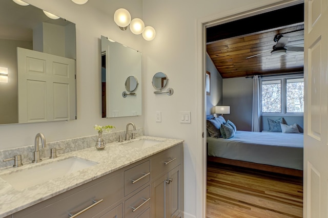 bathroom featuring ensuite bath, double vanity, wood ceiling, and a sink