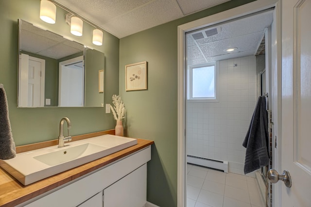 full bath featuring tile patterned floors, a baseboard heating unit, tiled shower, and vanity