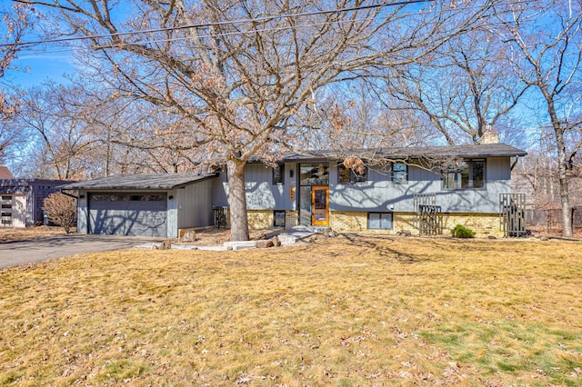 view of front of house with aphalt driveway, a garage, a front lawn, and a chimney