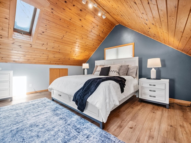 bedroom featuring baseboards, wooden ceiling, rail lighting, and light wood-style floors