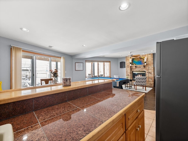 kitchen with tile countertops, open floor plan, plenty of natural light, and freestanding refrigerator