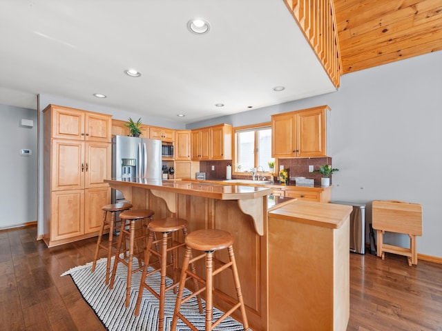 kitchen with a center island, dark wood finished floors, a breakfast bar area, stainless steel appliances, and backsplash