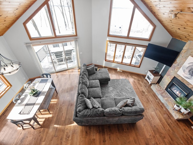 living area featuring wood ceiling, high vaulted ceiling, wood finished floors, and a glass covered fireplace