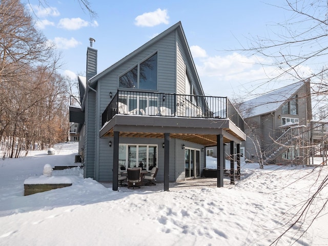 snow covered house featuring stairway and a chimney