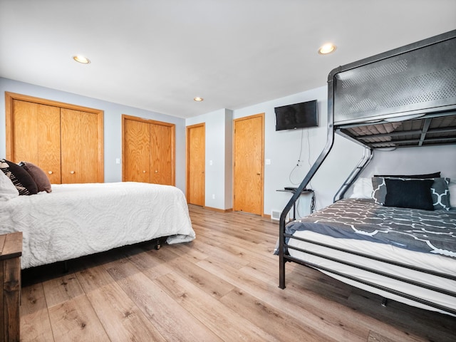bedroom with recessed lighting, baseboards, two closets, and light wood-style flooring