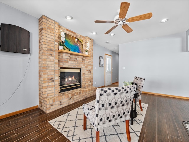 living area featuring wood finished floors, baseboards, recessed lighting, ceiling fan, and a brick fireplace