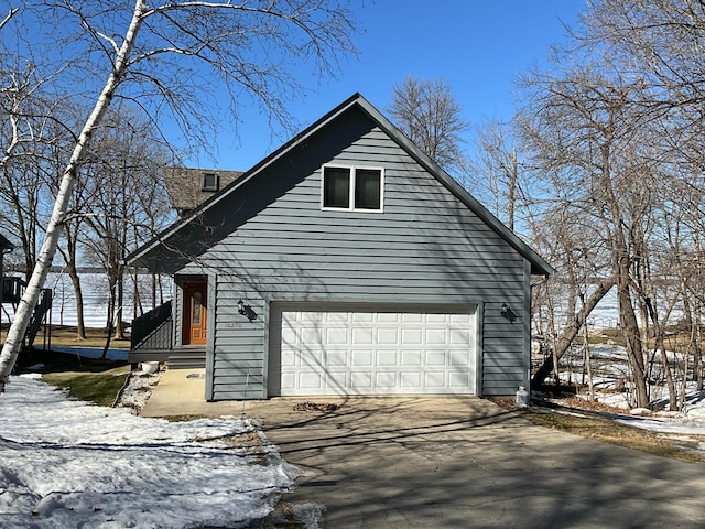 view of snow covered exterior with an attached garage and driveway