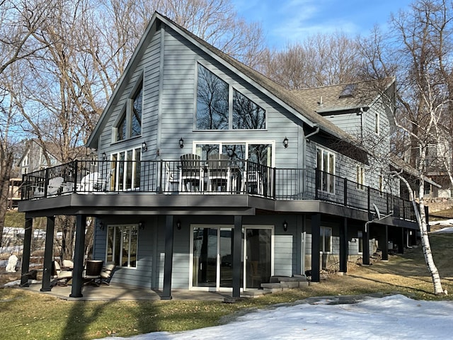 back of property with a patio area, a deck, and roof with shingles