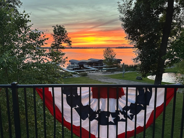 balcony at dusk featuring a water view