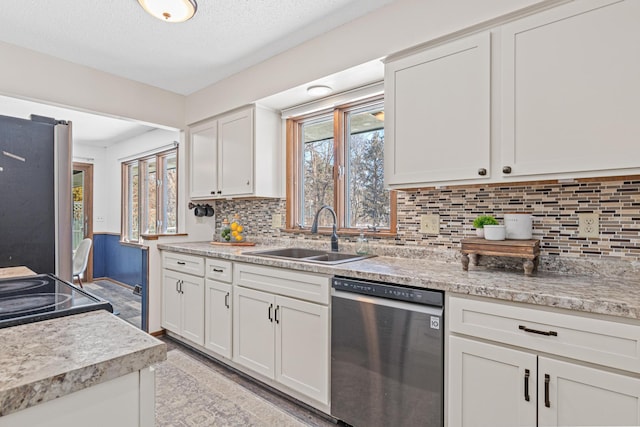 kitchen featuring stainless steel appliances, backsplash, white cabinetry, a sink, and a textured ceiling