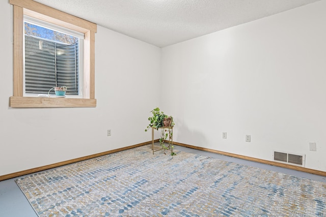 unfurnished room with a textured ceiling, visible vents, and baseboards