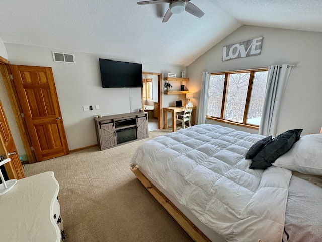 bedroom with a fireplace, lofted ceiling, light colored carpet, visible vents, and a textured ceiling