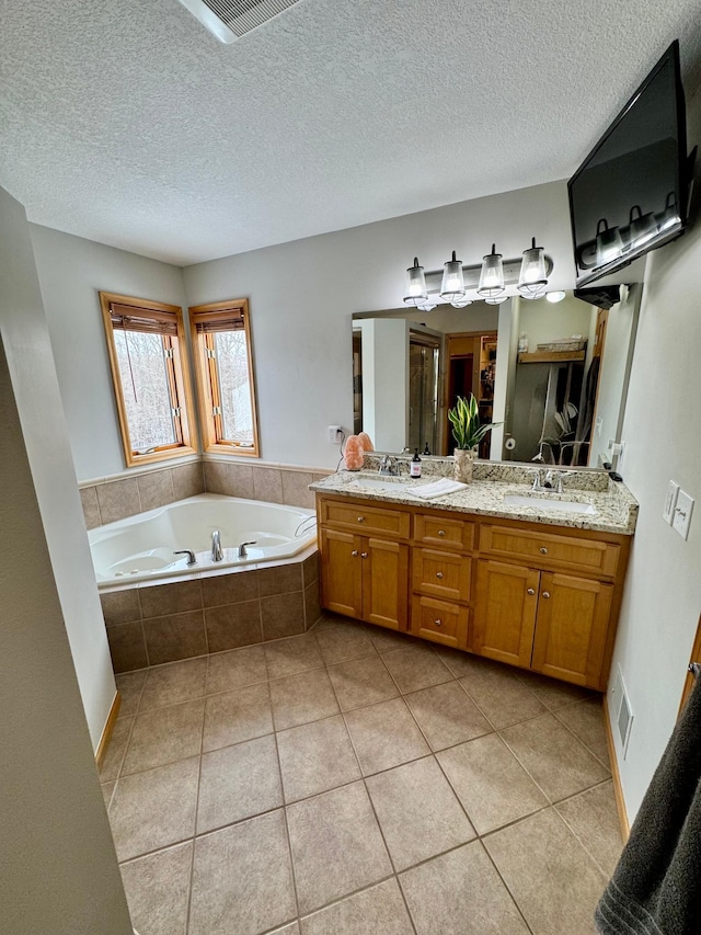 full bath with double vanity, visible vents, a bath, tile patterned floors, and a sink