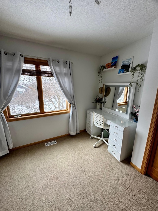 home office with a textured ceiling, baseboards, visible vents, and light colored carpet