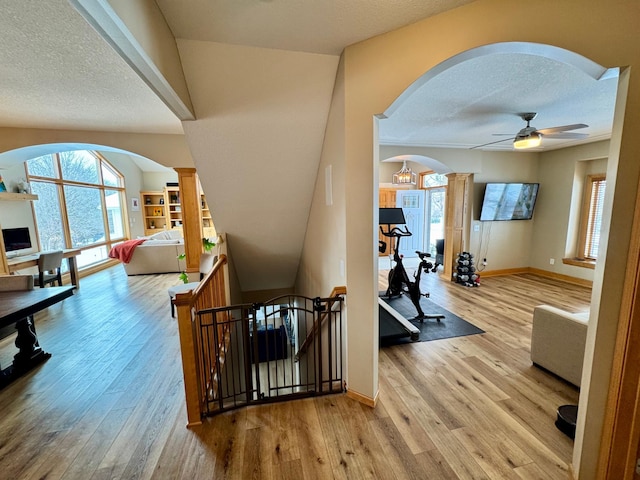 interior space with arched walkways, light wood-type flooring, an upstairs landing, and ornate columns