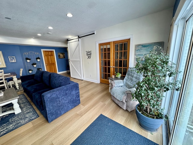 living room featuring recessed lighting, a barn door, a textured ceiling, wood finished floors, and baseboards