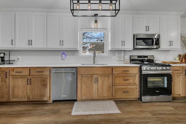 kitchen featuring a sink, appliances with stainless steel finishes, wood finished floors, and light countertops