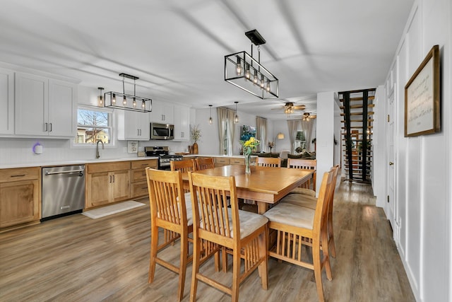 dining area with light wood finished floors and a ceiling fan