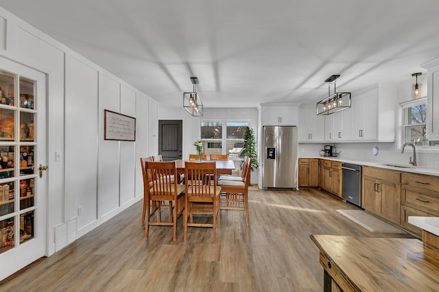 dining room featuring visible vents, a decorative wall, a healthy amount of sunlight, and light wood finished floors