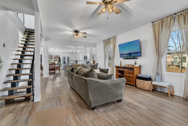 living room featuring stairway, light wood-style floors, and a healthy amount of sunlight