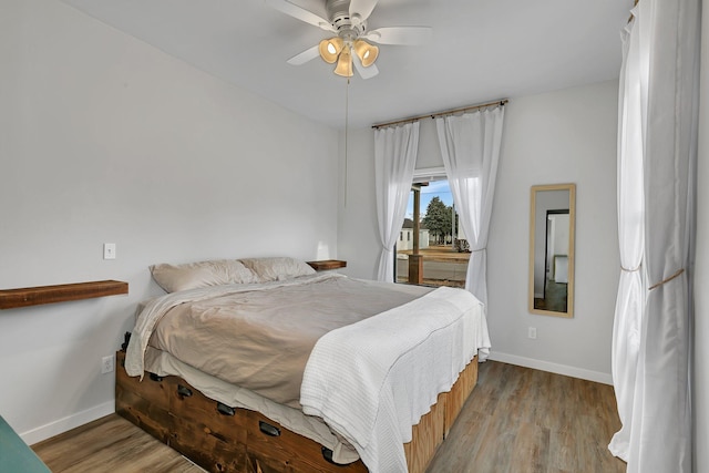 bedroom with a ceiling fan, wood finished floors, and baseboards