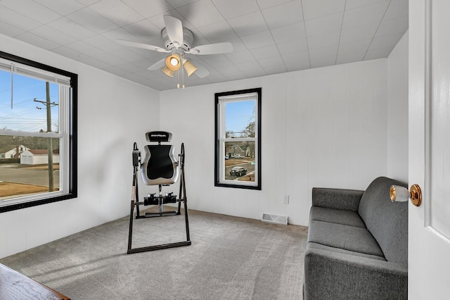 interior space with a ceiling fan, visible vents, and carpet floors