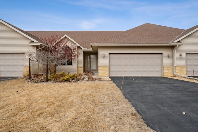 single story home with brick siding, driveway, an attached garage, and roof with shingles