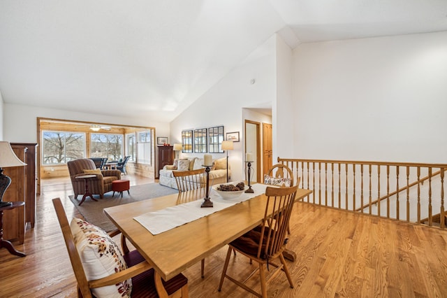 dining area with high vaulted ceiling and light wood finished floors