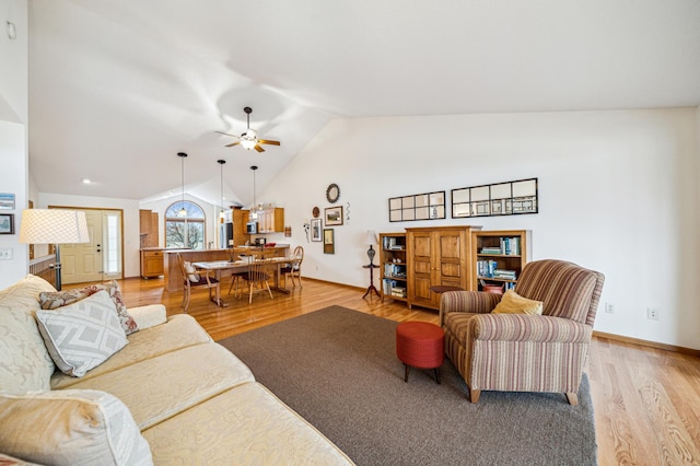 living room with light wood-style flooring, baseboards, vaulted ceiling, and a ceiling fan